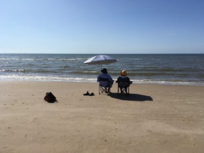 Echtpaar zittend in klapstoelen op het strand, kijkt naar de horizon.